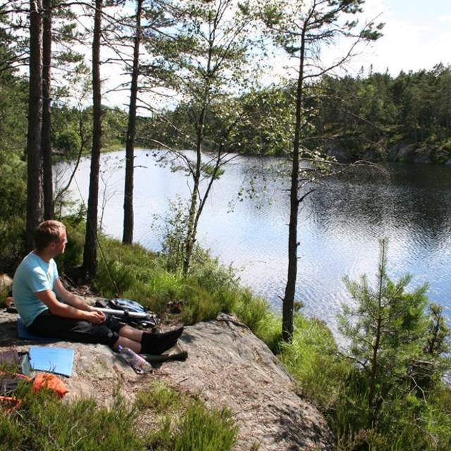 En gutt som sitter ved ett vann og titter utover