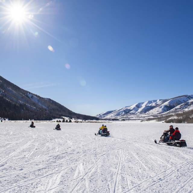 Group of snowmobiles in a wide-open field in Weber Canyon on sunny day.