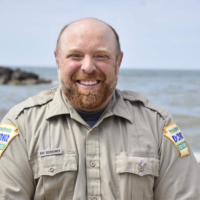 A man posing for a photo in front of a lake