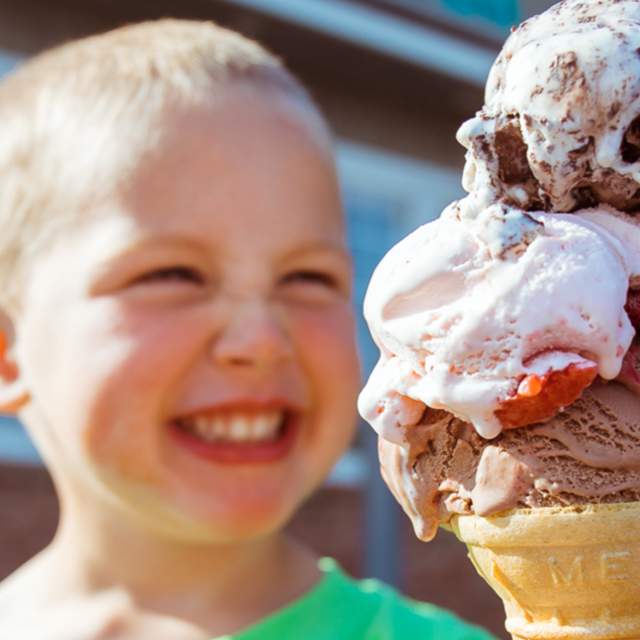 A young boy smiling at an ice cream cone with two large scoops of ice cream