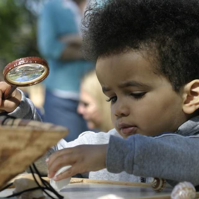 Child with a magnifying glass at the Roger Williams Park Zoo