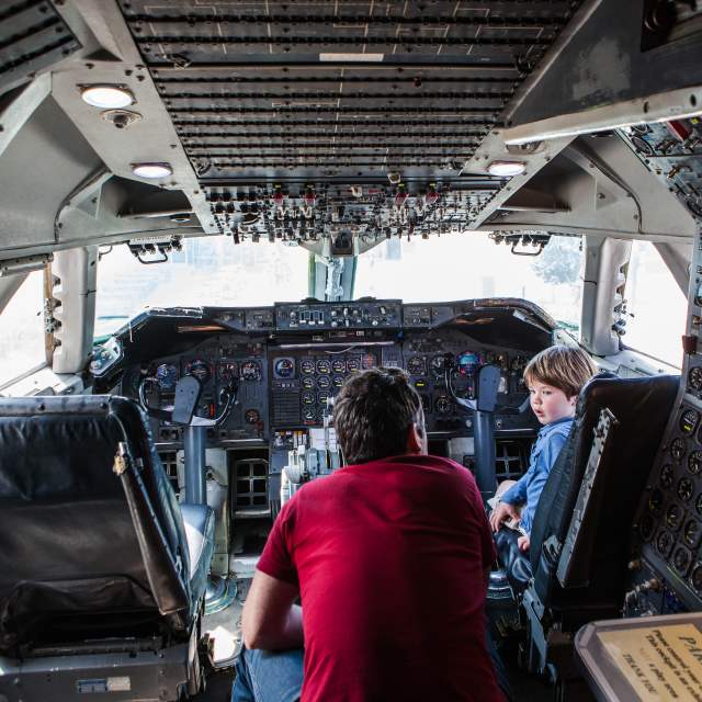 Kid experiencing the flight deck at Hiller Aviation Museum with a tour guide