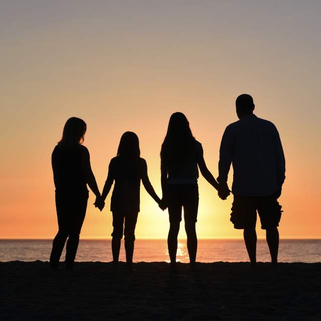 Family-of-four-looking-at-the-ocean-during-the-sunset