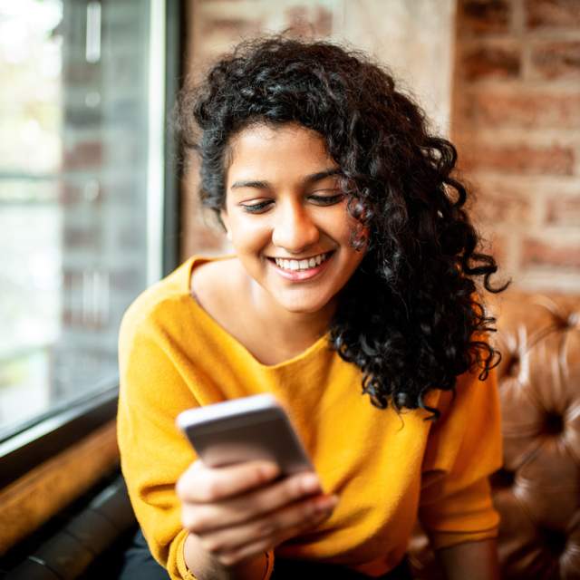 Woman smiling while looking at her mobile phone