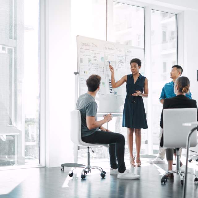 Campaigns-as-a-Service (CaaS) | Campaign Management - People in an office, one pointing to a chart whiteboard with statistics from a campaign