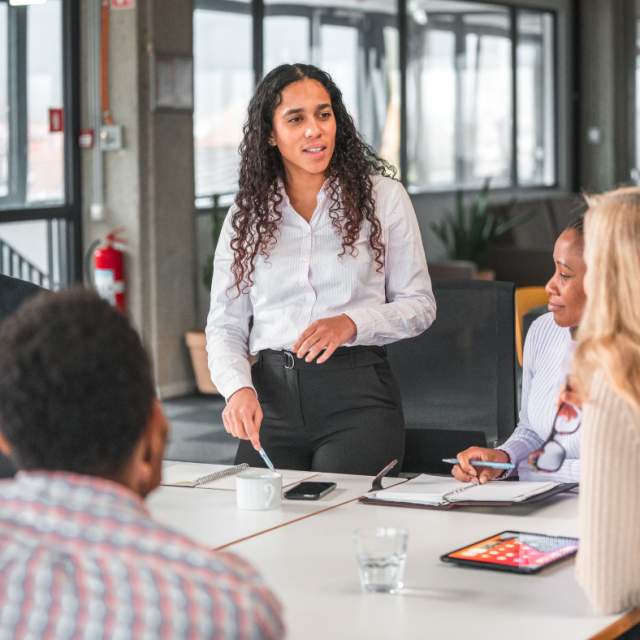 Team meeting with woman standing at table talking
