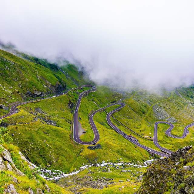A winding road twists through a lush, green mountainside.