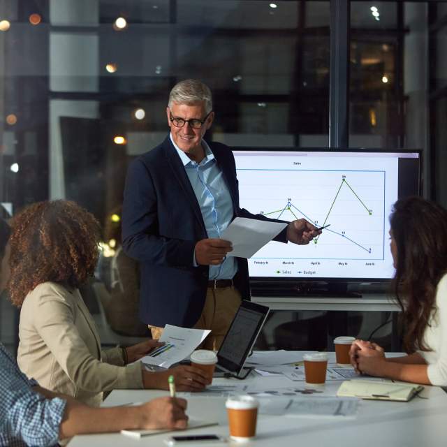 A consultant presents performance data and strategic insights to a team, illustrating a data‑driven approach to improving meetings sales results.
