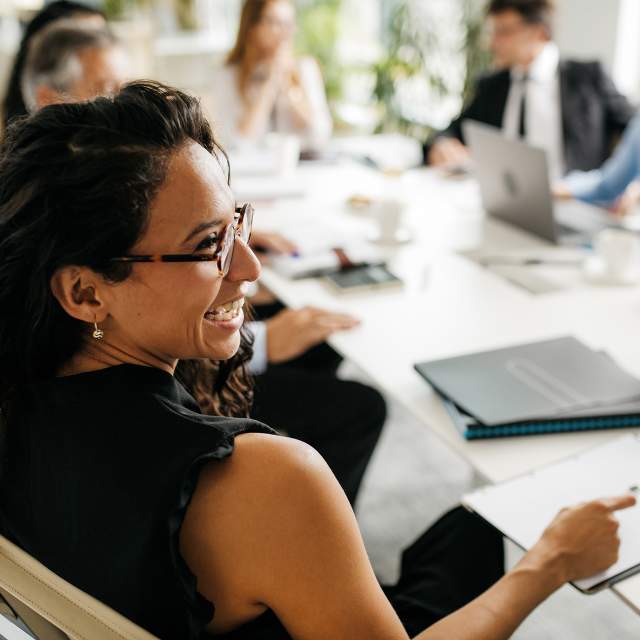 A woman glancing to her right and smiling during a meeting.