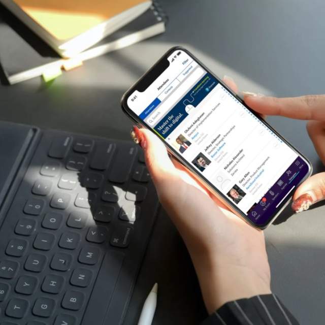Person holding cellphone above laptop