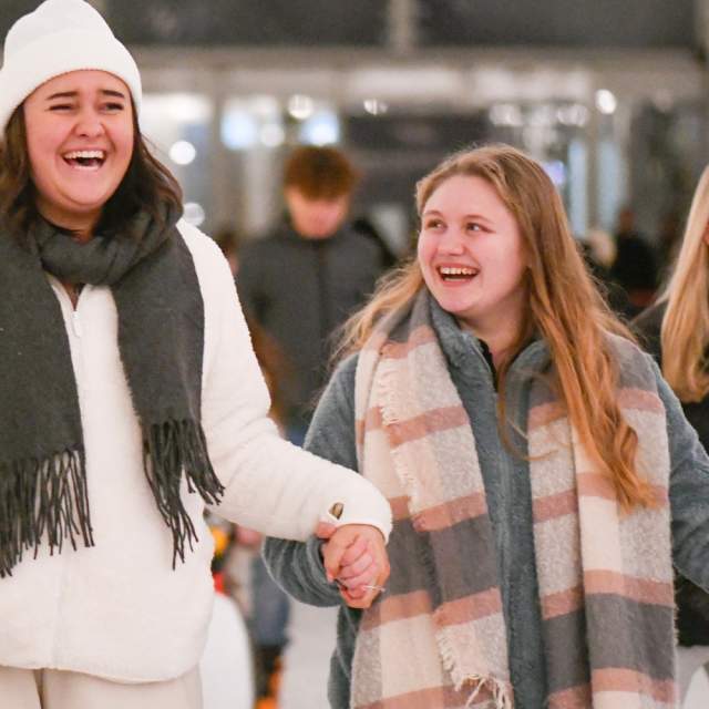 Two women holding hands ice skating laughing at Westquay On Ice