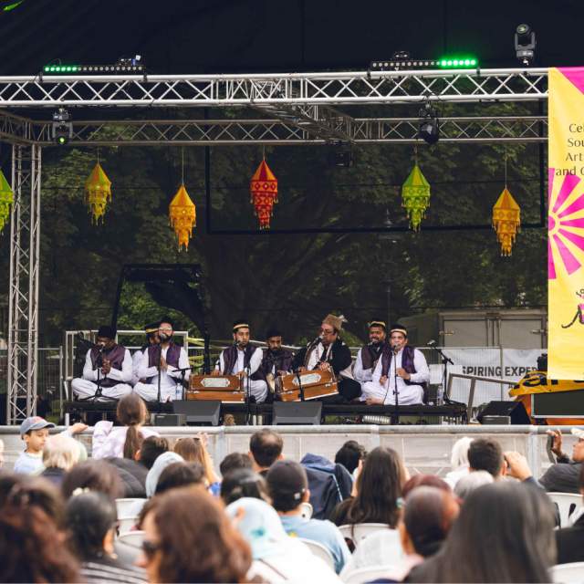 Back of crowd watching Khan Brothers on a stage at Southampton Mela Festival outside in Hoglands Park on a sunny day