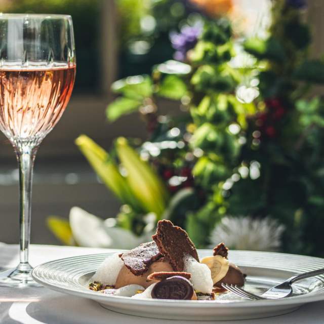 Fine dining plate of food next to a glass of wine on a table