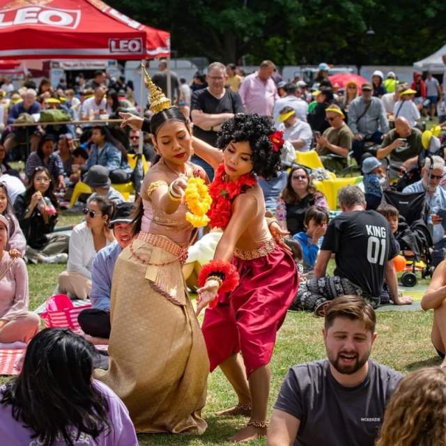 Crowd of people sat on the floor with two performancers dancing in the middle