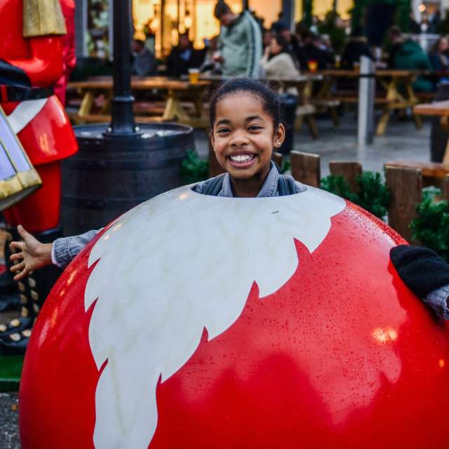 Girl smiling in Christmas bauble photo stand at Christmas Market