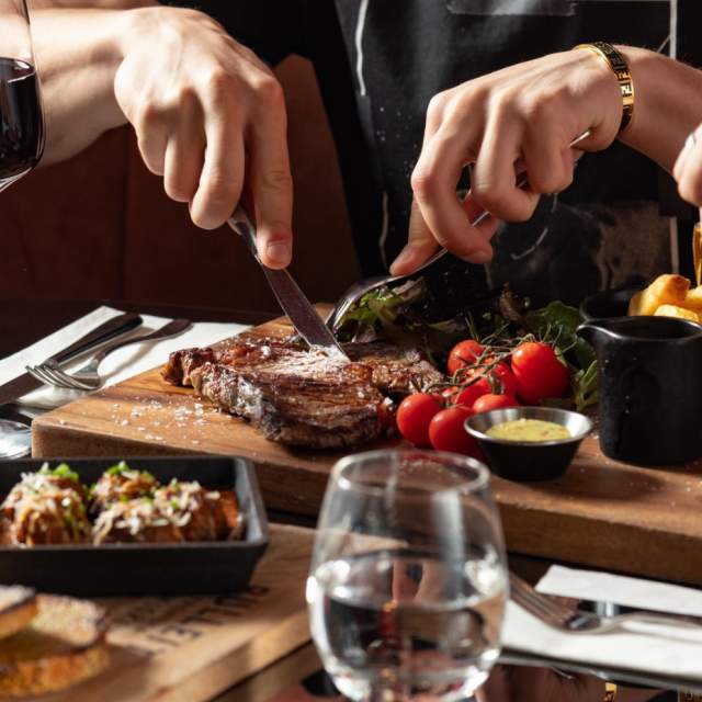 Close up of person cutting up a steak in a restaurant