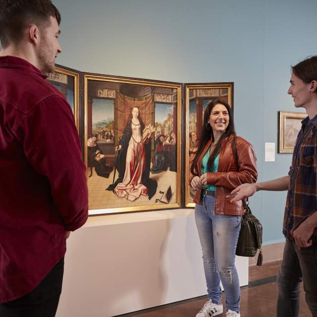 Group standing in front of a painting of a woman discussing artwork at Southampton City Art Gallery