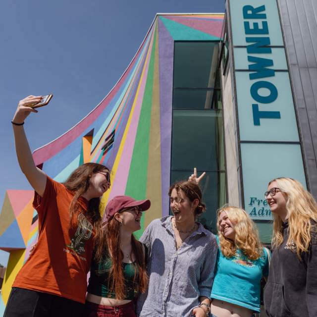 A group of young people take their photo in front of the colourful exterior of Towner gallery, Eastbourne