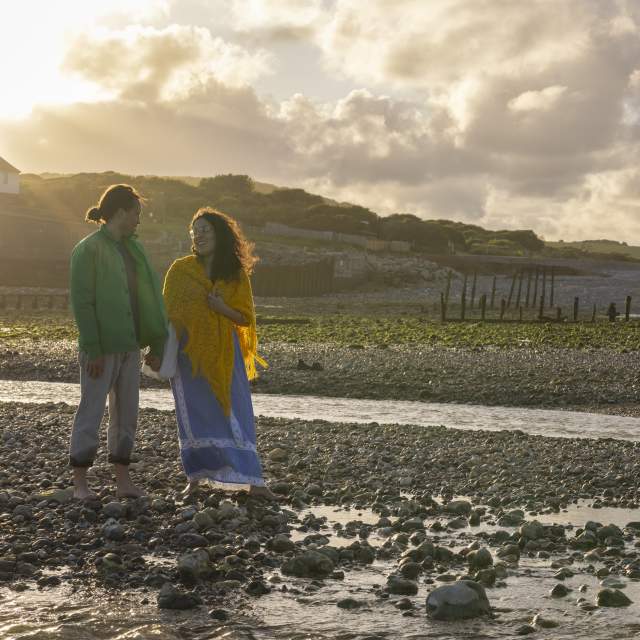 A couple stand on the rocky shore at Cuckmere Haven near Seaford Head, Sussex