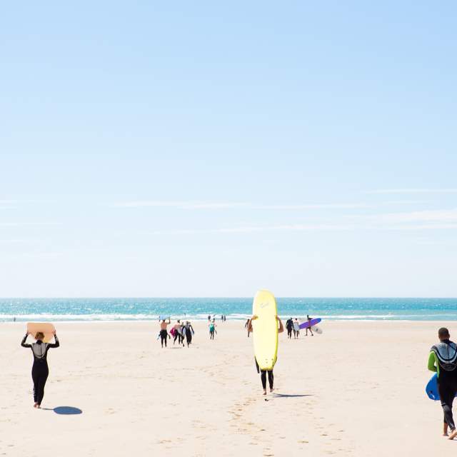 Surfers running down Llangennith Bay Beach