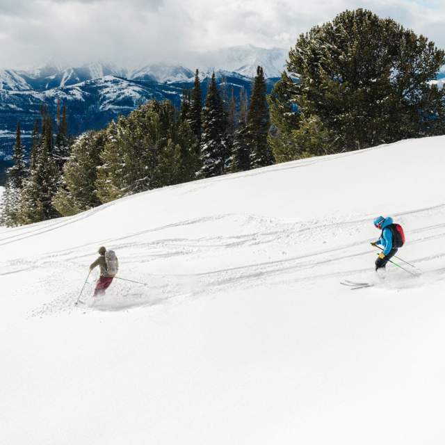 Three people backcountry skiing through snowy terrain in the Absaroka Mountains, Park County, Wyoming.