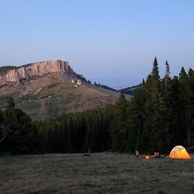 Campsite and campers with a tent and a campfire at dusk in Wyoming.