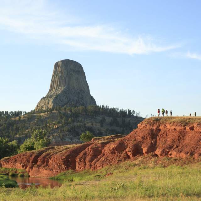 Hiker walking along a trail surrounded by lush greenery in Wyoming at sunrise
