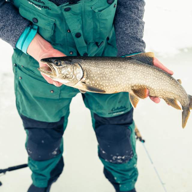 Angler ice fishing on a frozen lake with fish in hands in Wyoming.