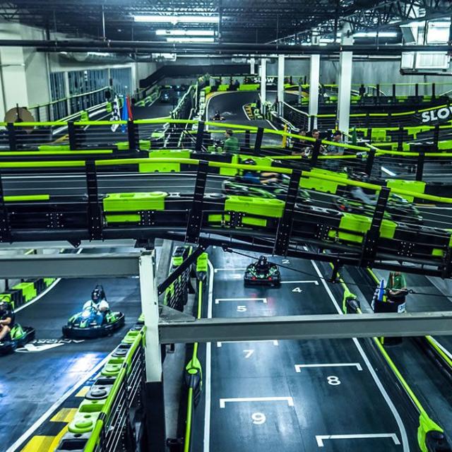 Several drivers race along the multi-level tracks at Andretti Indoor Karting & Games