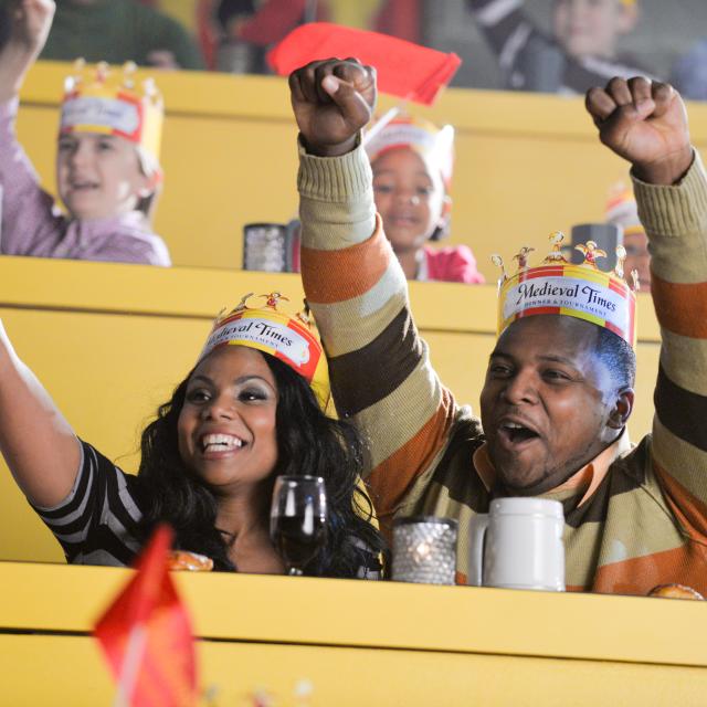 A couple cheering from their seats at Medieval Times Dinner and Tournament.