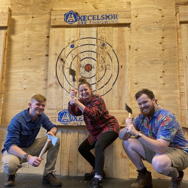 A group of friends pose with axes at Axecelsior Axe Throwing in Orlando, Florida.