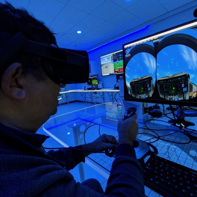A man operates a joystick of a virtual reality flight simulator computer at Orlando Science Center.