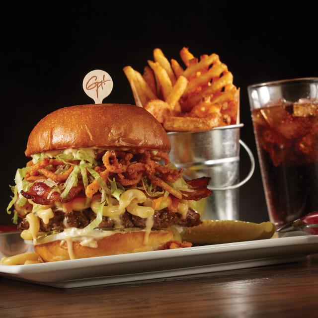 Guy Fieri's Bacon Mac-n-cheese Big Bite Burger, fries, and a beverage on a table at Planet Hollywood.