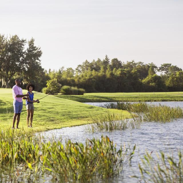 A couple fishing on the shore at JW Marriott Orlando, Grande Lakes.