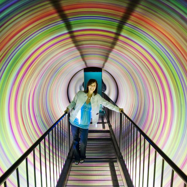 A woman makes her way through the colorful spiraling tunnel at WonderWorks.