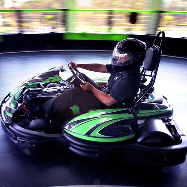 A driver leans into a curve while riding a go-kart at Andretti Indoor Karting & Games