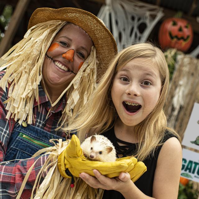 Scarecrow holding a hedgehog with a girl at Gatorland's Gators, Ghosts and Goblins Halloween event