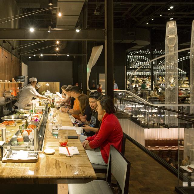Guests dining at the sushi bar inside Morimoto Asia restaurant at Disney Springs