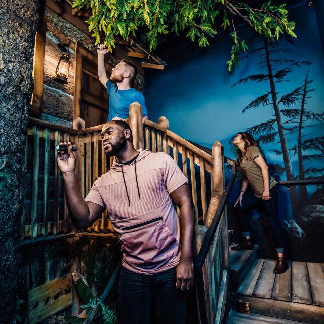 Guests searching for clues outside a cabin at The Escape Game Orlando