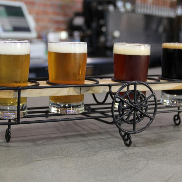 A flight of beer samples displayed apropros in wire-framed bi-plane-shaped holder at Crooked Can Brewing.