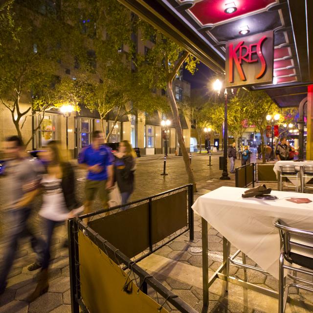 People walking by Kres restaurant at Church Street Station in downtown Orlando at night