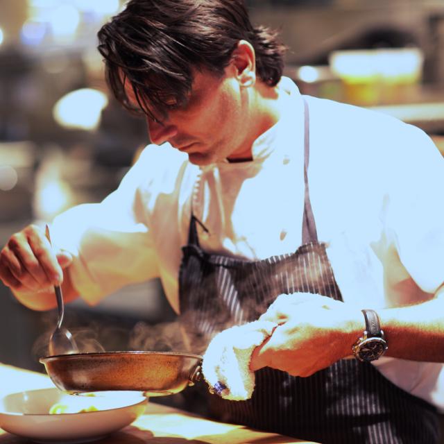 Chef Brandon McGlamery preparing a dish at Luma on Park restaurant.