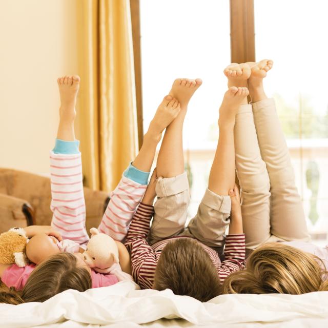 Children lying down on a bed with legs in the air