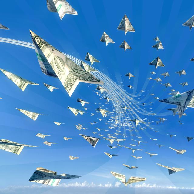 Paper airplanes made of dollar bills flying in a blue sky