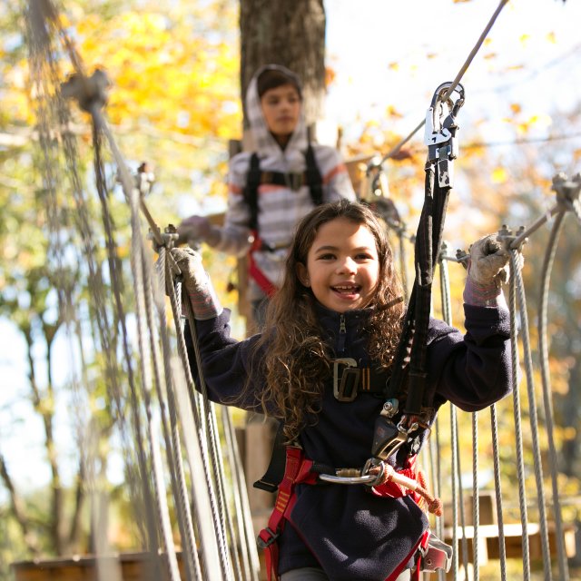 A girl and boy enjoy the high ropes course at an adventure park in the Pocono Mountains
