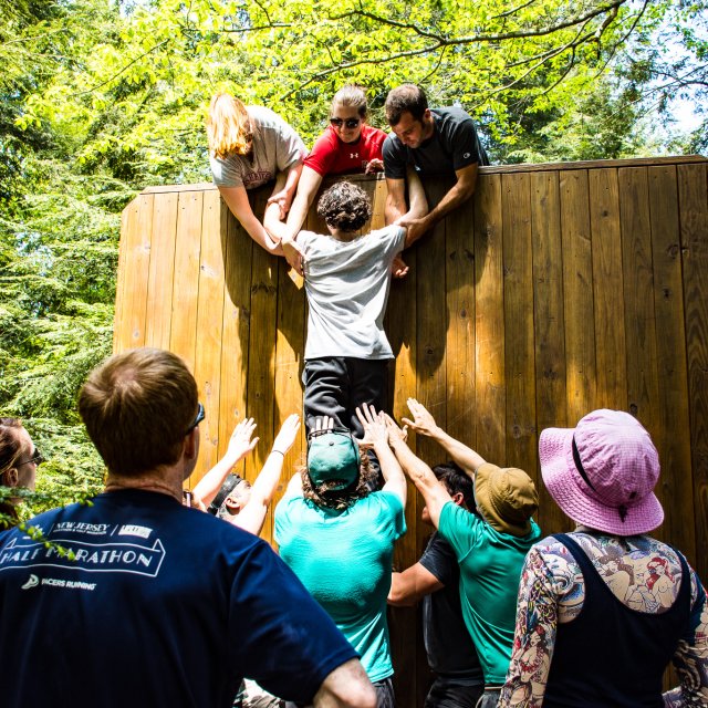 A group of people climbing a wall during a team building activity
