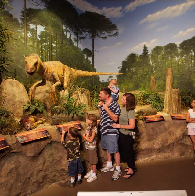 family observing the dinosaur exhibit at the Creation Museum