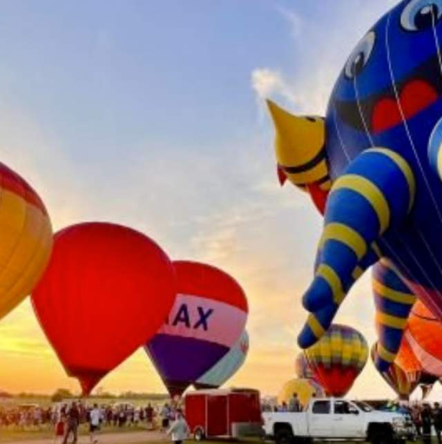 The sun rises while hot air balloons launch at Taste and Glow