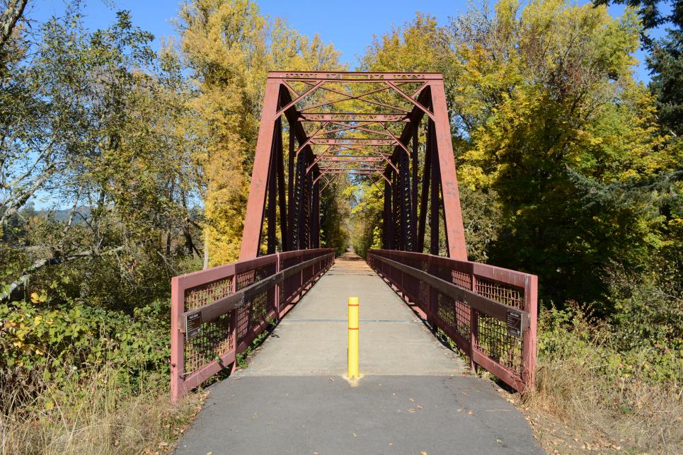 The Mosby Creek railroad trestle bridge in "Stand by Me" paved for cycling and rolling. Yellow trees in the background.