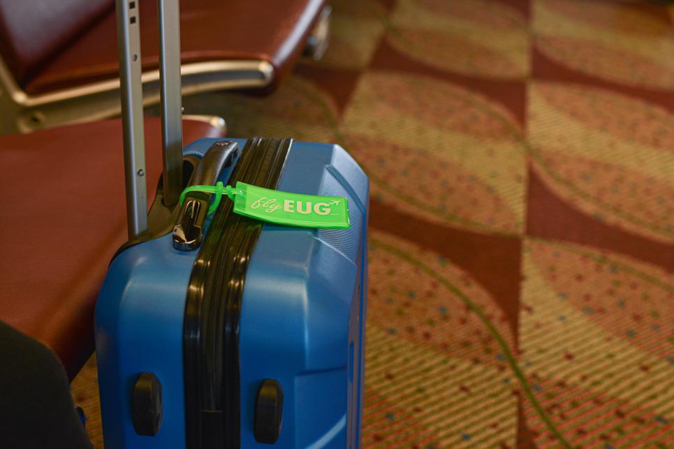 A blue hardcase suitcase with green EUG tag.